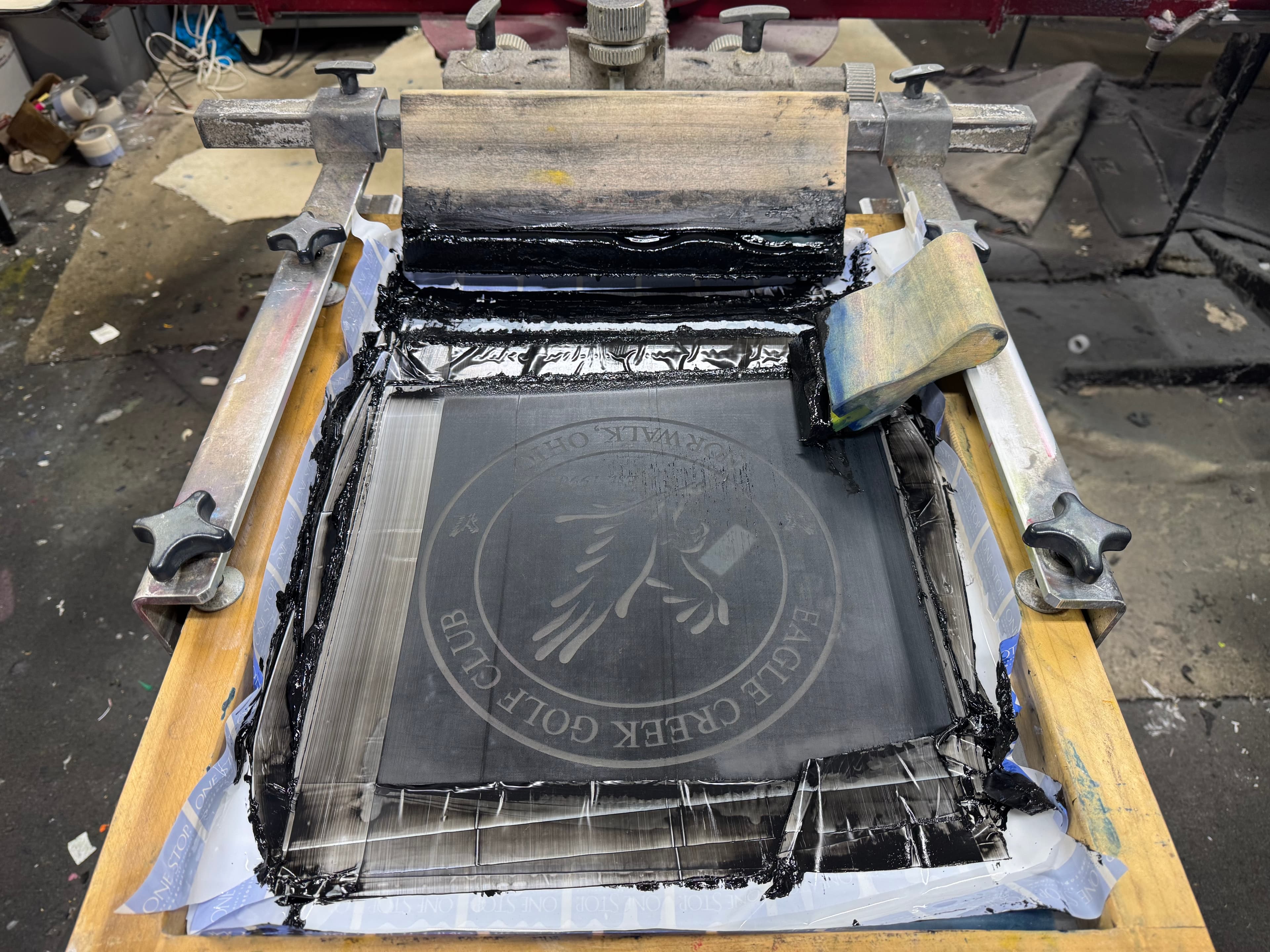 Black ink applied to a screen printing stencil featuring the Eagle Creek Golf Club logo.
