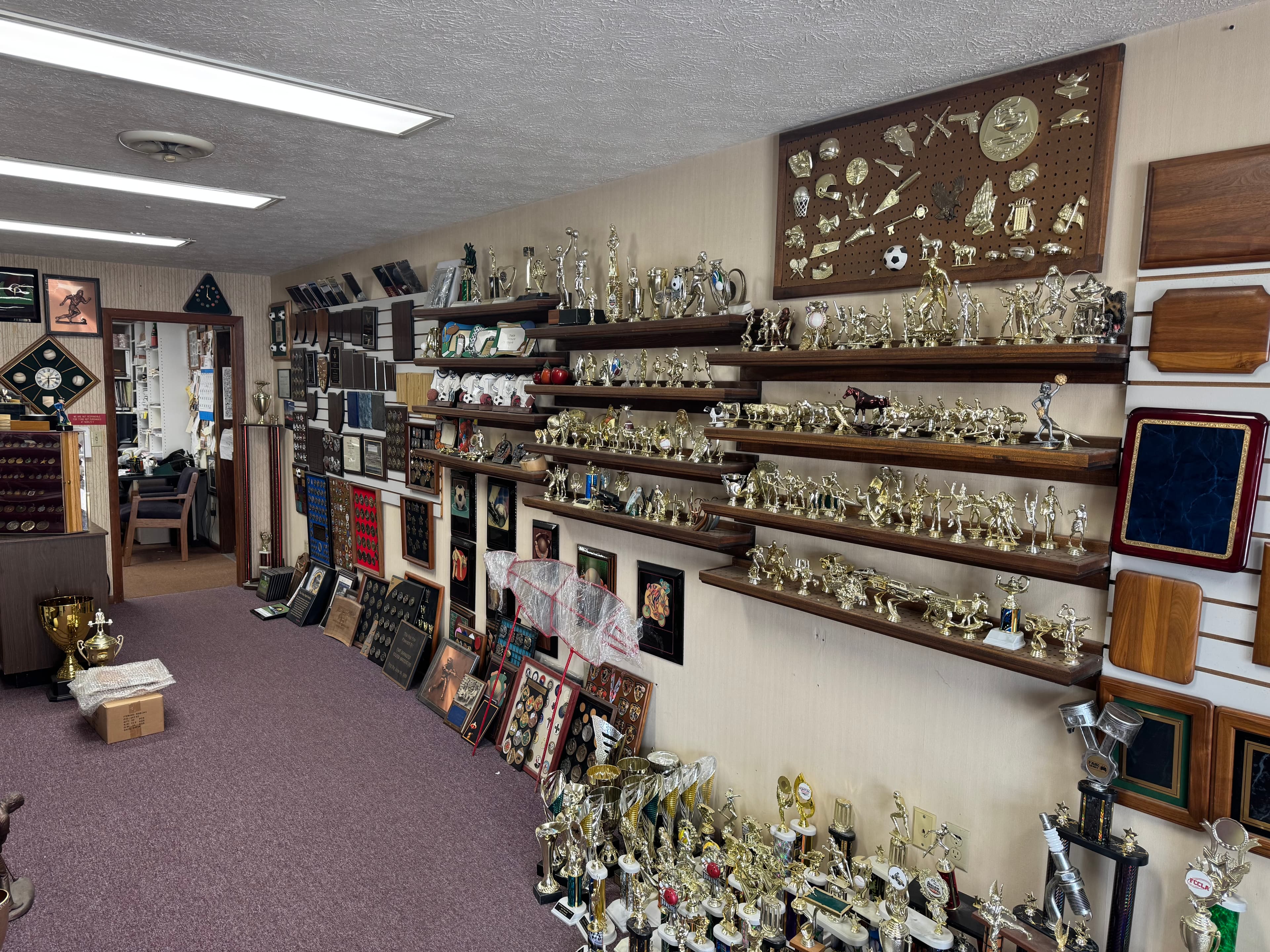 Densely packed shelves and walls featuring a vast collection of gold trophies and plaques.